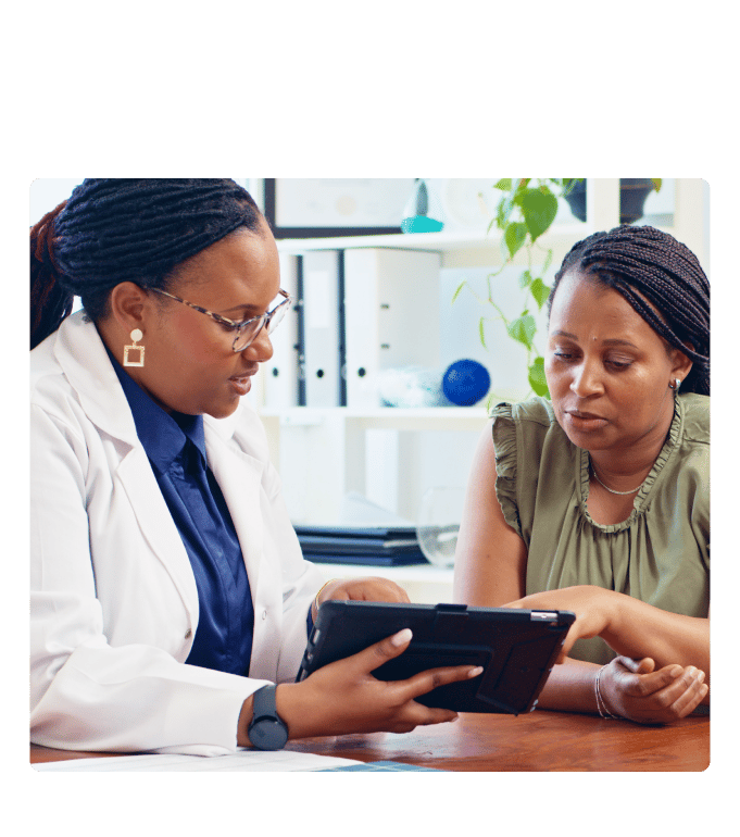 A provider in a lab coat reviews care data on a tablet with a member, collaborating on personalized health outcomes—a glimpse into the future of preventive care, where partnerships like these are making grand strides toward healthier lives.