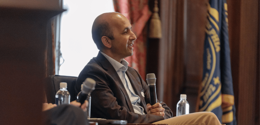 Nirav Vakharia, MD, chief operating officer of Marathon Health, delivers remarks at an event in Philadelphia, with draped curtains and flags framing the backdrop at the Union League.