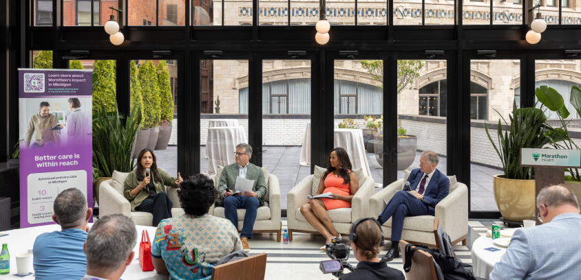Four panelists, Jim Kirk, Avani Sheth, MD, Chris Pricco, and LaShawn English, speak to a seated audience in a glass atrium at the Shinola Hotel in Detroit. A Marathon Health banner promotes advanced primary care in Michigan and new locations coming soon in the Detroit metro area.