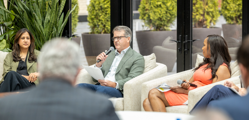 Chris Pricco, a speaker in a green blazer, addresses the audience between two fellow panelists during a Marathon Health discussion on substance use disorder and access to care at the Shinola Hotel in Detroit.