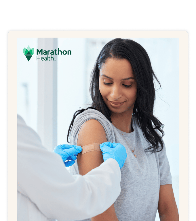 Marathon Health provider applying a bandage to a patient's arm during a primary care visit.