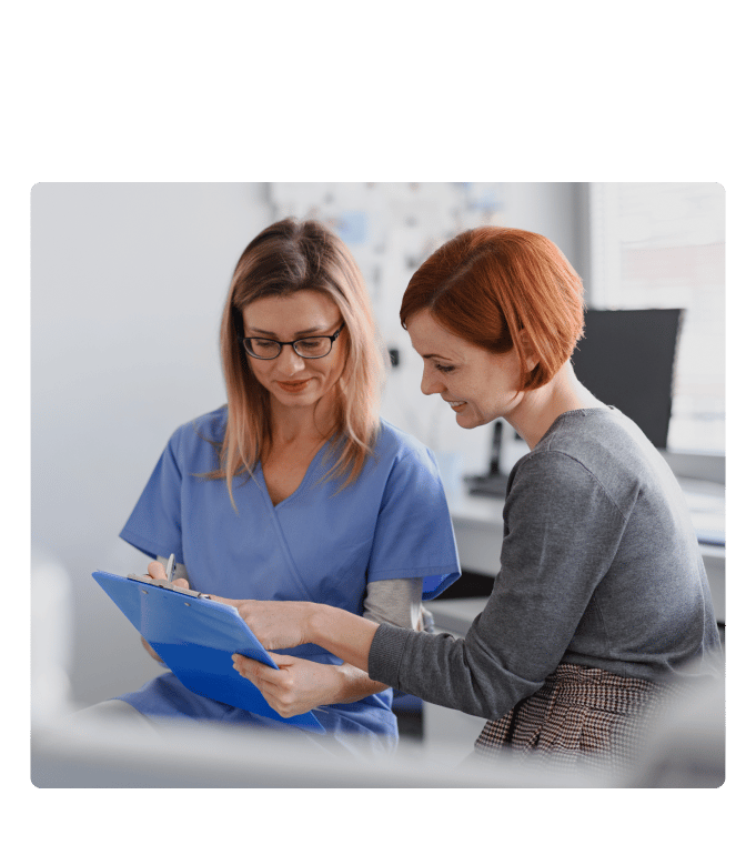 Healthcare provider in blue scrubs reviewing a clipboard with a person at an onsite health center.