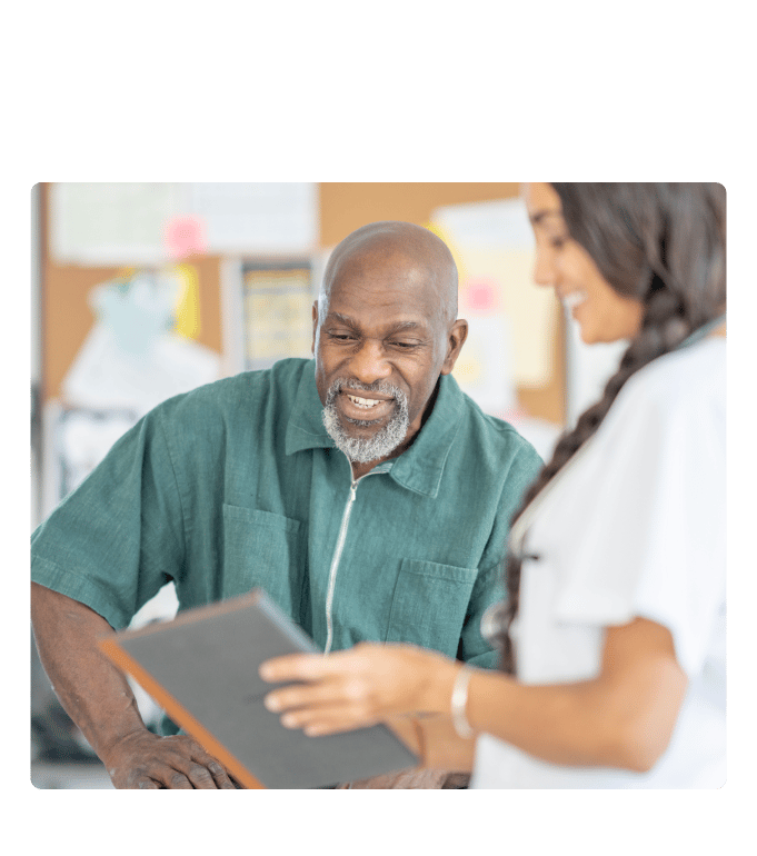 Physician assistant in a white coat reviewing a tablet together with patient.