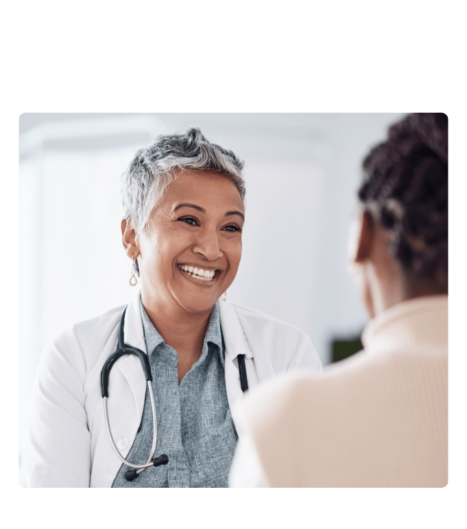 Healthcare provider in a white coat and stethoscope smiling during a conversation at an employee health center