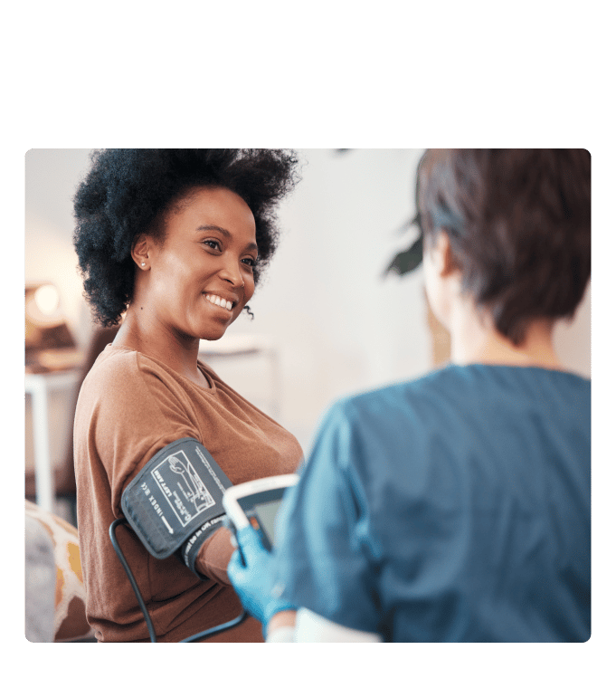 Person smiling while a gloved healthcare provider takes a blood pressure reading during a biometric screening