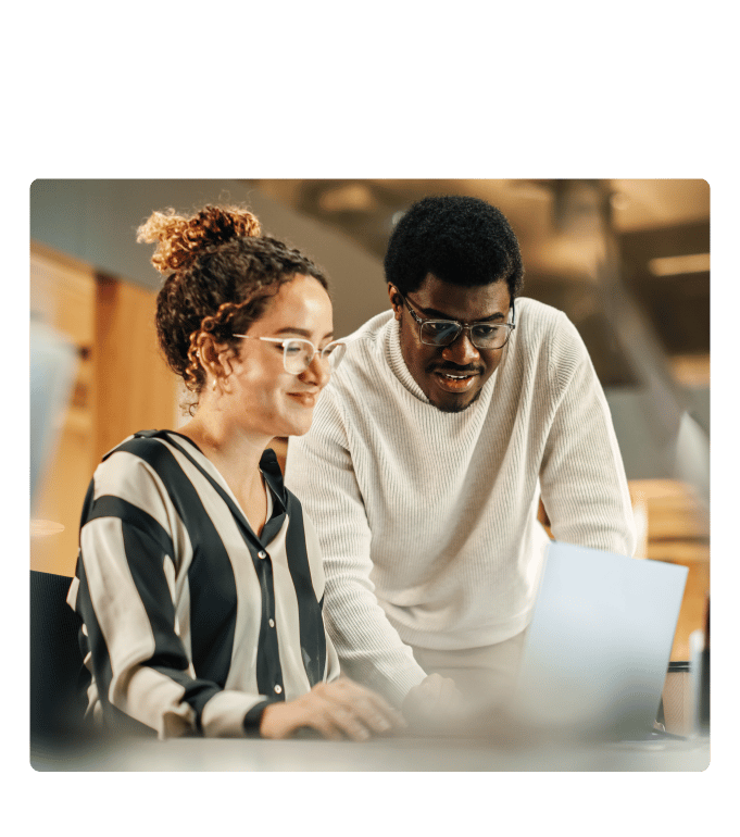 Two people collaborating at a laptop in a bright office setting.