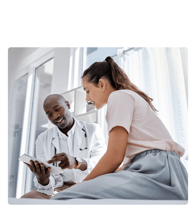 Healthcare provider in a white coat reviewing chronic condition data with a person seated in a clinical setting.