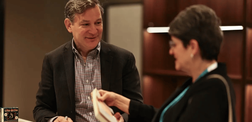 Dan Harris speaking with a woman before signing an autograph.