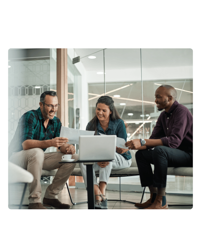 Three financial services employees laughing and reviewing documents together.