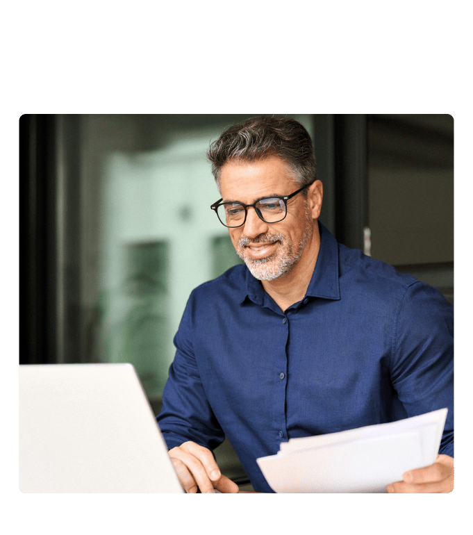 Person in glasses reviewing information on onsite wellness centers beside a laptop in an office setting.