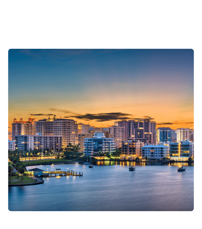 Sarasota city skyline reflecting over calm waterways at sunset.