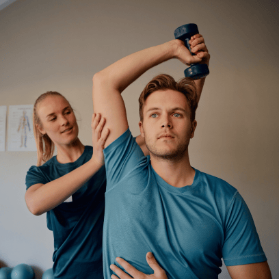 Physical therapist assisting patient with overhead shoulder exercise using a dumbbell.