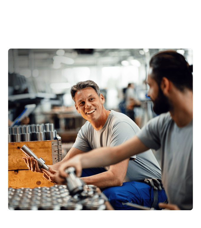 Two smiling Briggs & Stratton employees handling metal parts.