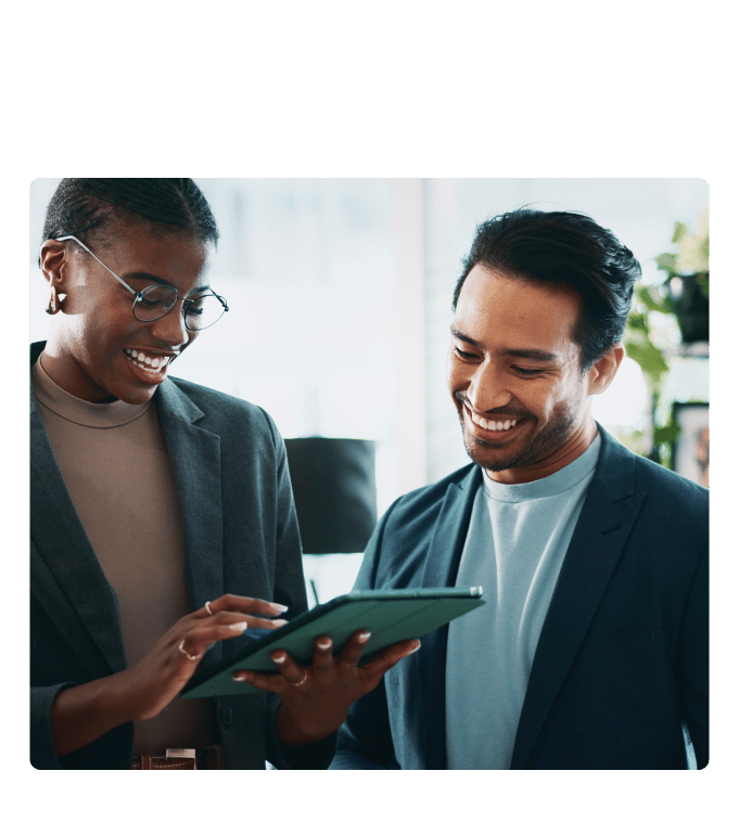 Two professionals smiling while reviewing employee benefits on tablet together in an office setting.