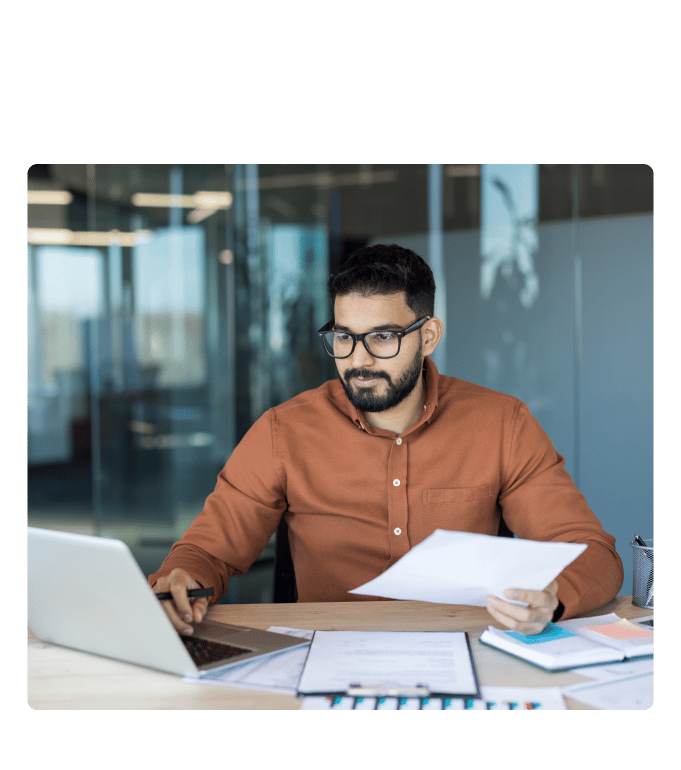 Person at a desk reviewing US healthcare costs while working on a laptop in an office setting.