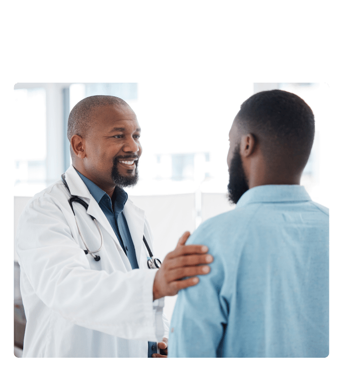 Healthcare provider in a white coat and stethoscope placing a hand on a person's shoulder in a clinic setting.