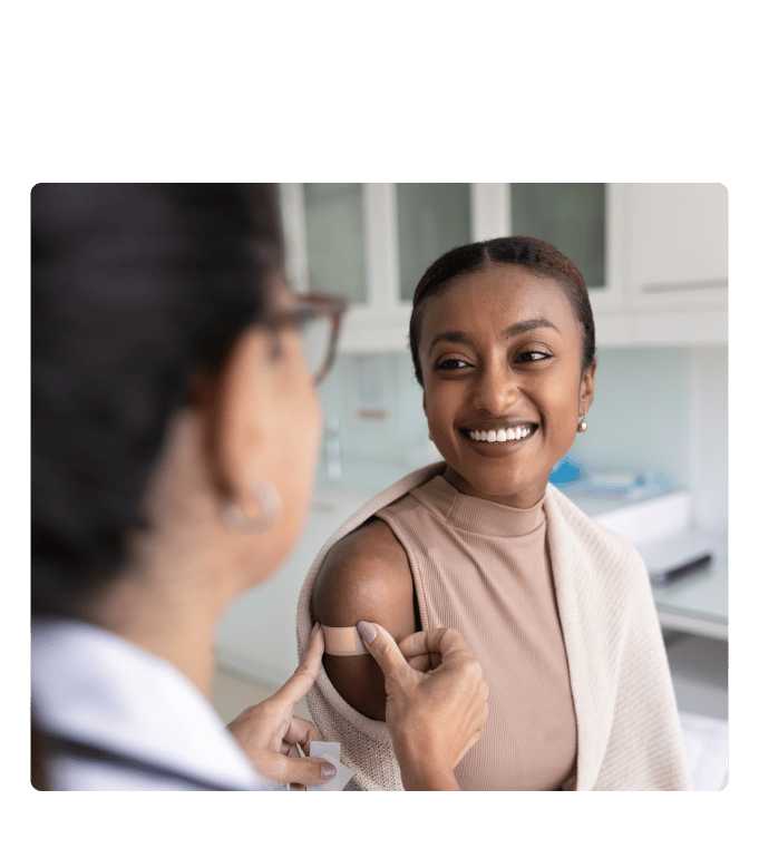 Dr. Natasha Parekh applying a bandage to a person's arm in a clinical setting.