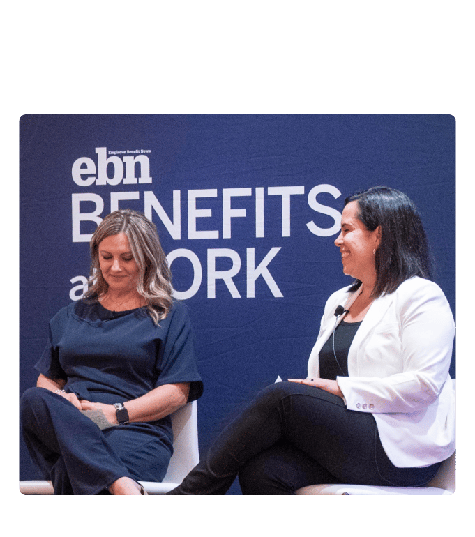 Two speakers seated on stage at the EBN Benefits at Work conference, engaged in conversation in front of a branded backdrop.