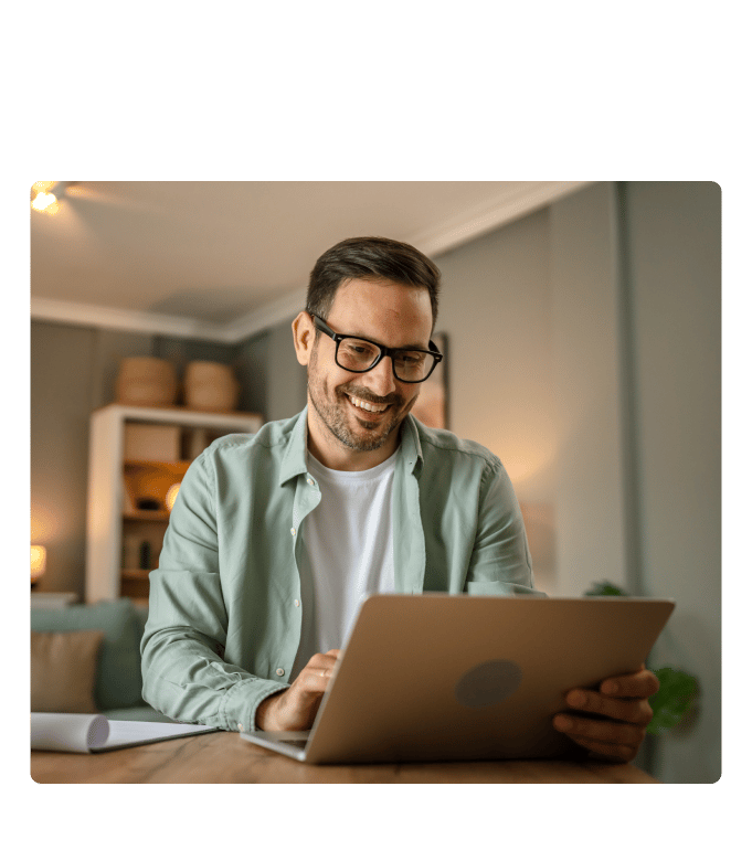 Person smiling while using a laptop at a home desk during a virtual care session.