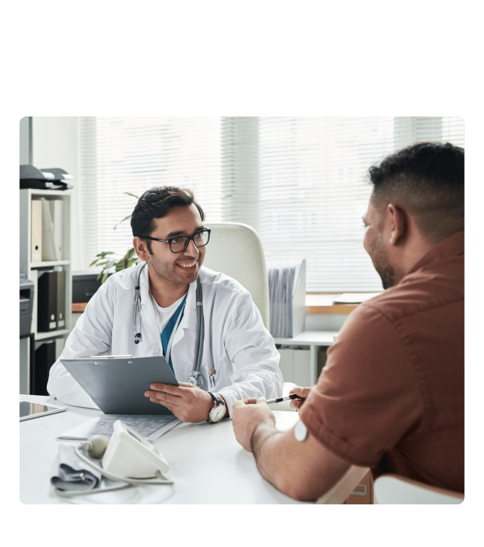 Doctor in a white coat reviewing a clipboard with a person at a health center desk.
