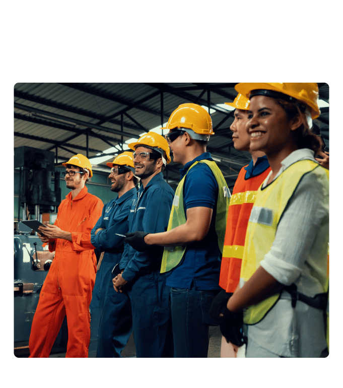 Group of workers in hard hats and safety vests standing together in an industrial facility, smiling