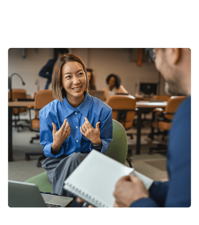 Person smiling and speaking during a one-on-one interview in an open office.