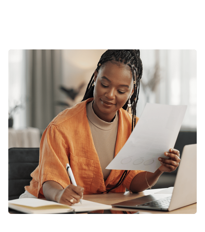Employee reviewing healthcare cost reduction strategies and taking notes at a desk with an open laptop nearby.
