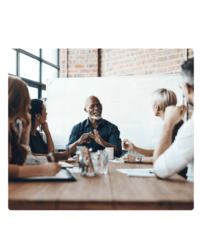 Group of employees seated around a conference table in discussion.