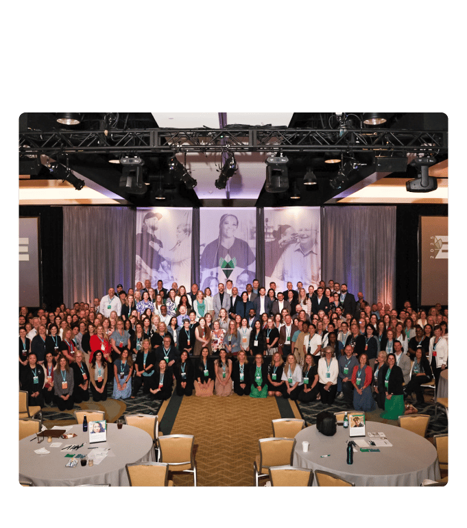 Large group of attendees posing in a ballroom at the Engage 2025 conference.
