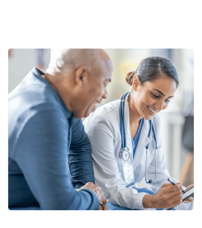 Physician smiling while writing notes during a consultation with a patient.