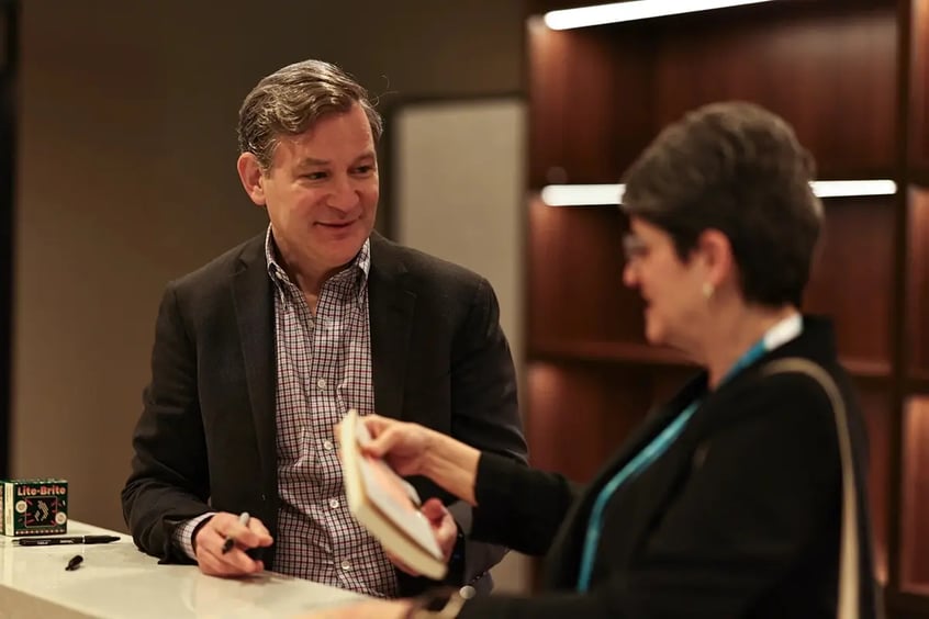 Dan Harris speaking with a woman before signing an autograph.