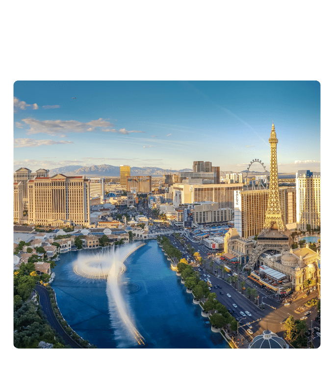 Aerial view of the Las Vegas Strip skyline with hotels, the High Roller, and Bellagio fountains under a blue sky