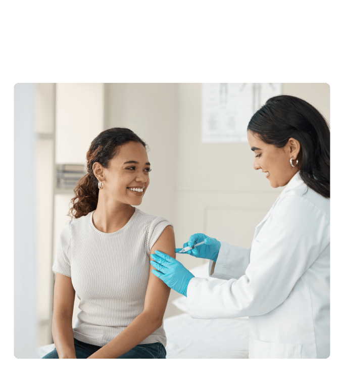 Healthcare provider in a white coat and blue gloves administering a flu shot to a person in a clinic setting.