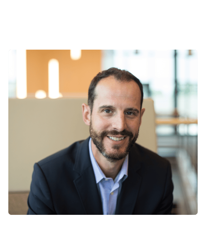 Dr. Jeff Wells smiling in a dark blazer and light blue shirt in a modern office