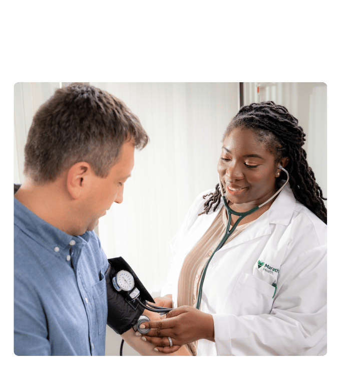 Healthcare provider in a white coat taking a person's blood pressure at a Marathon Health health center.