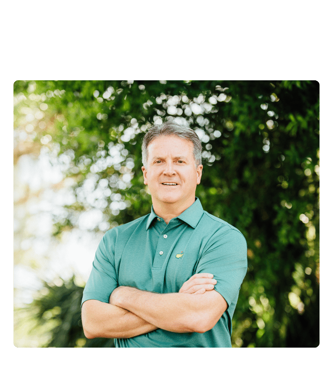 Chris Pricco, Marathon Health CEO, standing outdoors with arms crossed and smiling, with green trees in the background