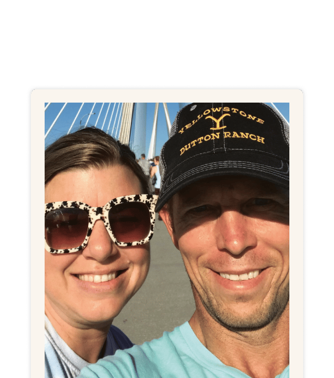 Brennan Killian smiling on a bridge in a Yellowstone cap and teal shirt, posing with another person
