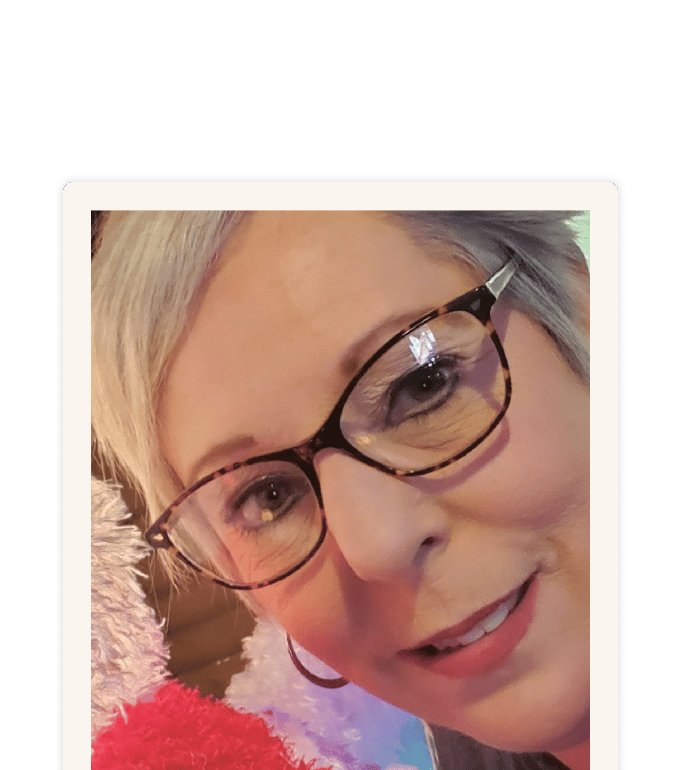 Rebecca Morris smiling in a close-up selfie, wearing tortoiseshell glasses and a red fluffy top