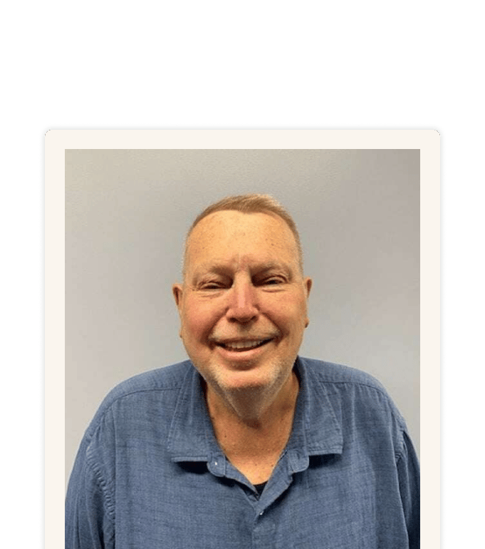 Bob Brennan smiling in a blue button-up shirt against a neutral gray background