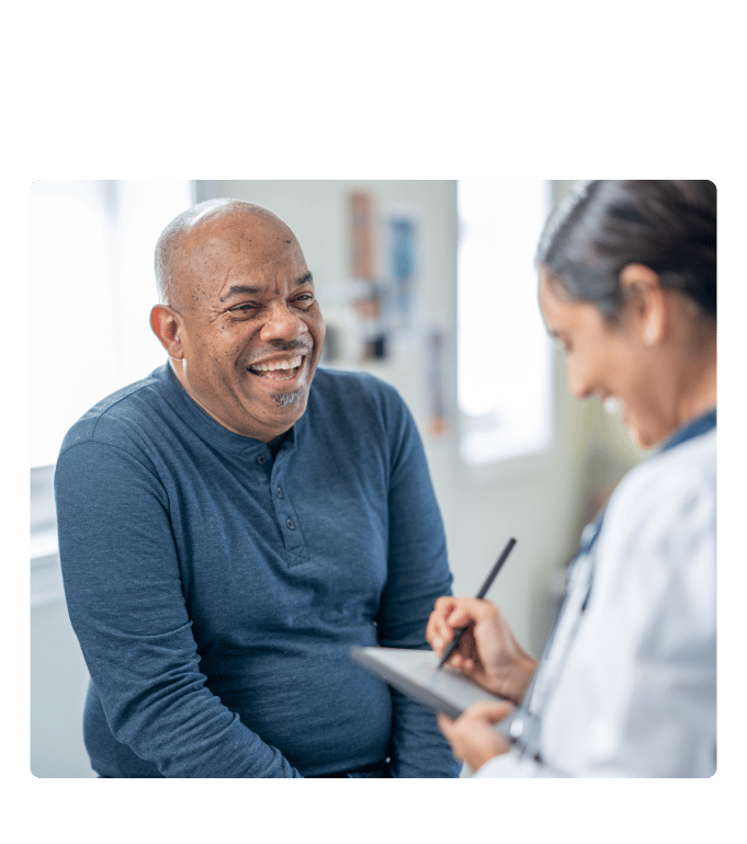 Smiling patient in consultation with a physician taking notes on a tablet.