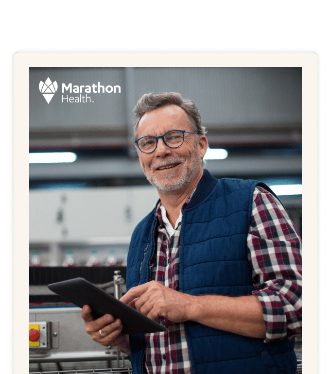 A smiling worker in glasses and a vest with a tablet at a production line