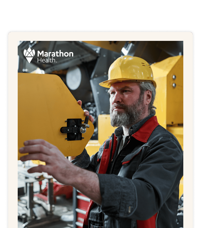 A worker in a yellow hard hat adjusting a panel on yellow machinery