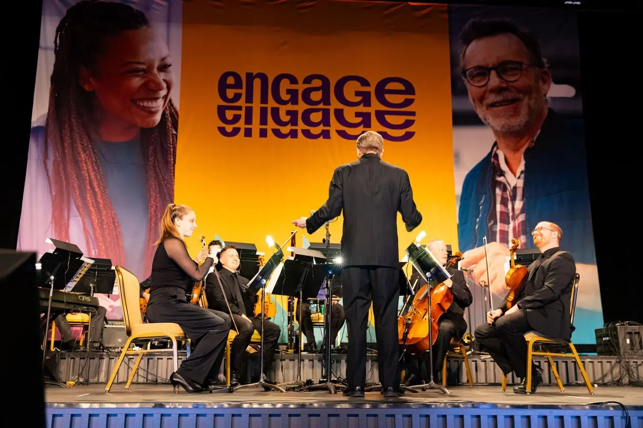 Orchestra performing beneath the ENGAGE banner