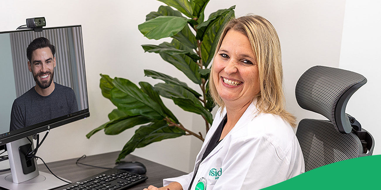 doctor smiling in front of a computer while on a virtual call