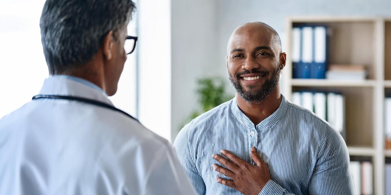 Patient wearing blue and white striped button down shirt smiling at a medical provider