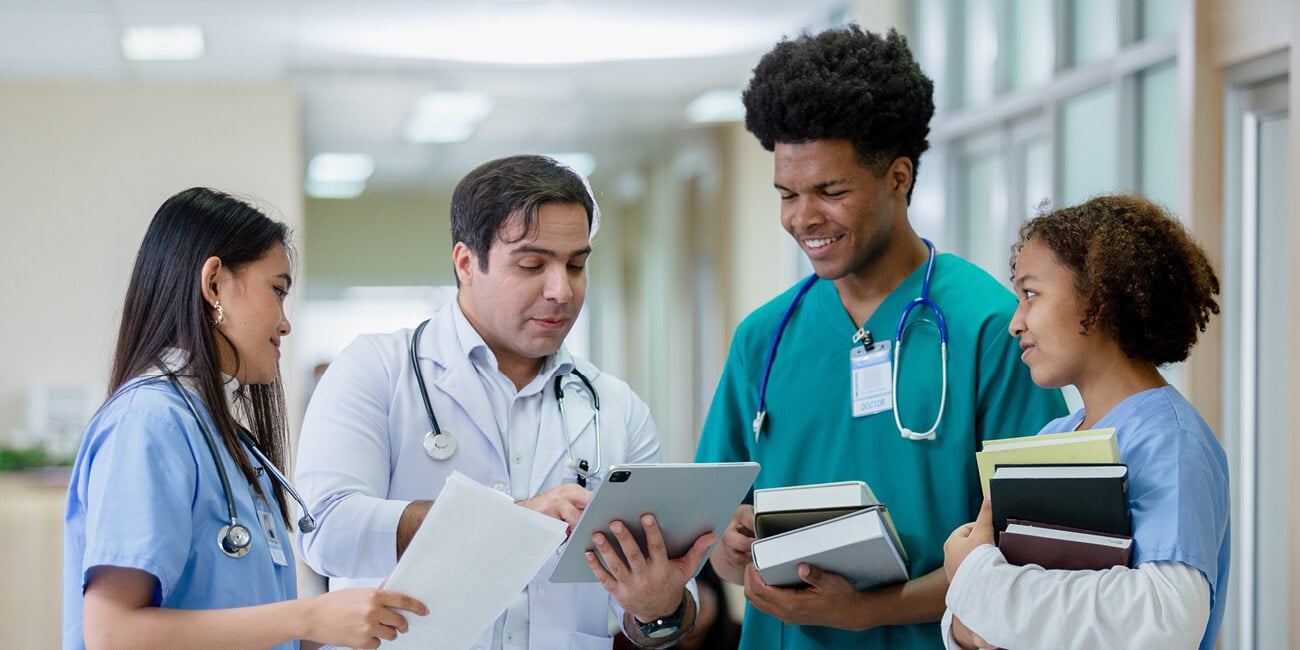 Provider teaching medical students in a clinic hallway