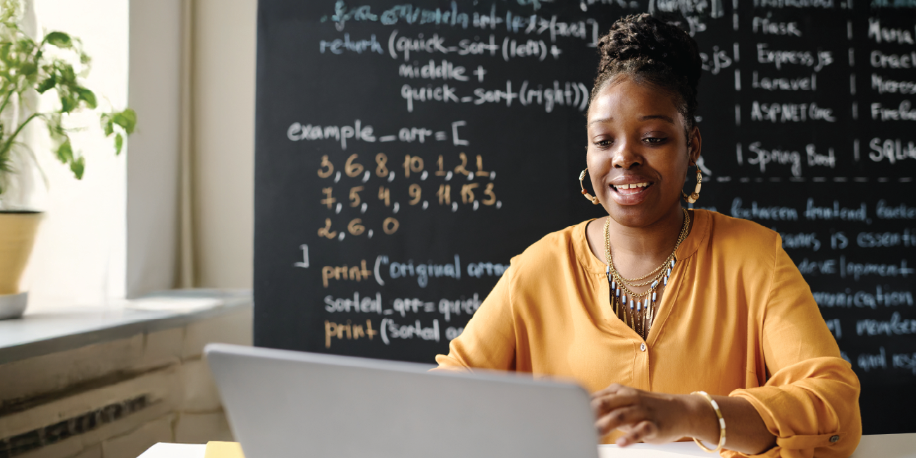 A teacher smiling at her desk while on a virtual healthcare visit with her provider.