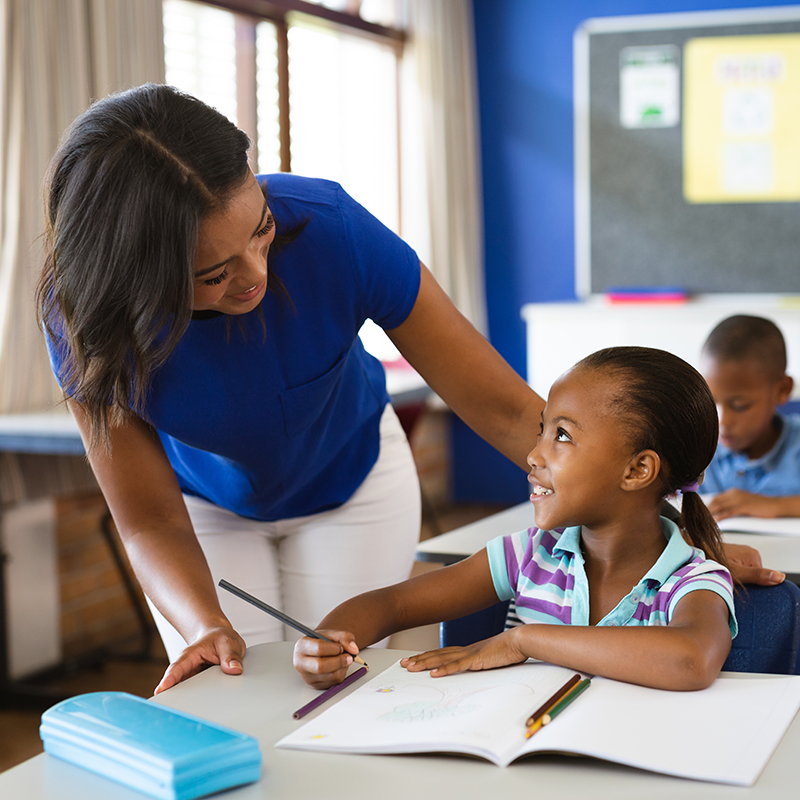 A teacher bending over and smiling at her student