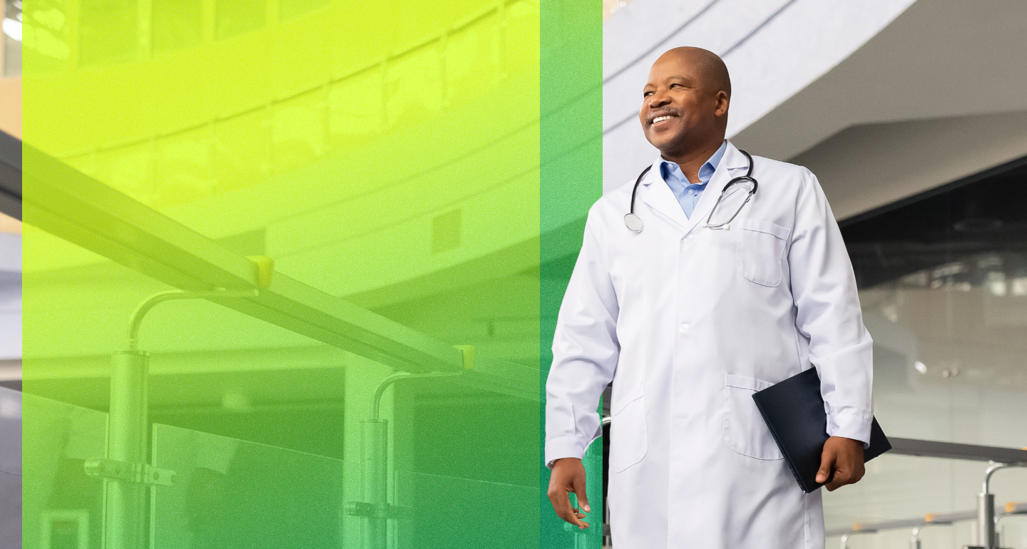 Smiling CHG Healthcare provider in a white coat and stethoscope holding a folder in a modern indoor setting.