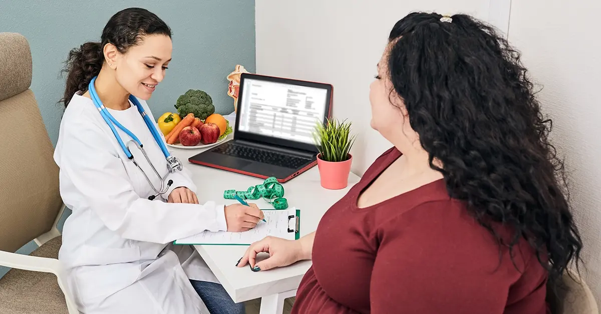 Doctor writing a prescription for a GLP-1 medication for weightloss in the presence of an overweight patient.